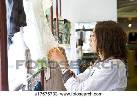 Young woman shopping at clothing store View Large Photo Image Stock Image - Young woman shopping at clothing store. Fotosearch