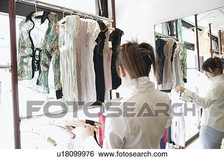 Stock Photograph - Young woman shopping at clothing store. Fotosearch