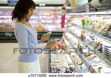 Stock Image - Young woman shopping at supermarket. Fotosearch