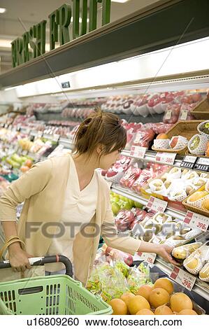 Stock Image - Young woman shopping at supermarket. Fotosearch