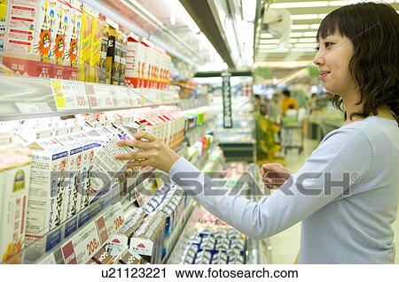 Stock Image - Young woman shopping at supermarket. Fotosearch
