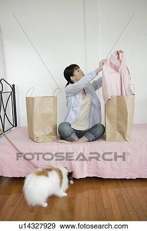Young woman taking out shirt from shopping bag View Large Photo Image Stock Photo - Young woman taking out shirt from shopping bag. Fotosearch