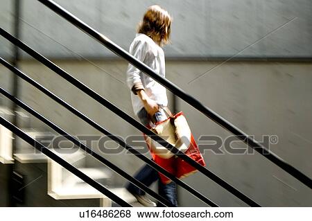 Stock Photo - Young woman walking down stairs, blurred motion. Fotosearch