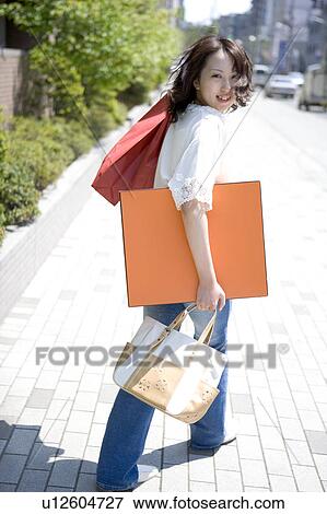 Stock Photo - Young woman walking with shopping bags. Fotosearch