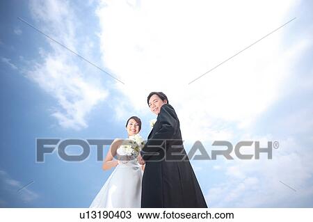 Stock Image - Bride and groom looking at camera. Fotosearch