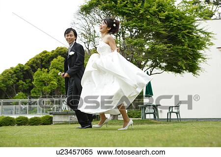 Stock Photography - Bride and groom running on lawn. Fotosearch