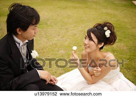 Stock Image - Bride and groom sitting on lawn. Fotosearch