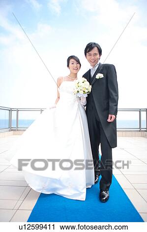 Stock Image - Bride and groom standing and looking at camera. Fotosearch