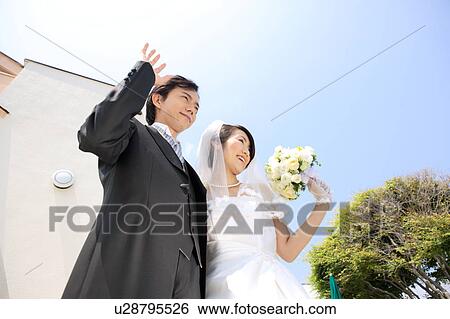 Stock Photograph - Bride and groom waving hands. Fotosearch