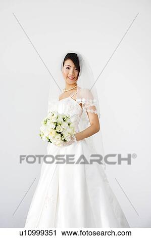Stock Image - Bride holding bouquet of flowers. Fotosearch