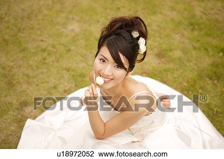 Stock Image - Bride sitting on lawn. Fotosearch