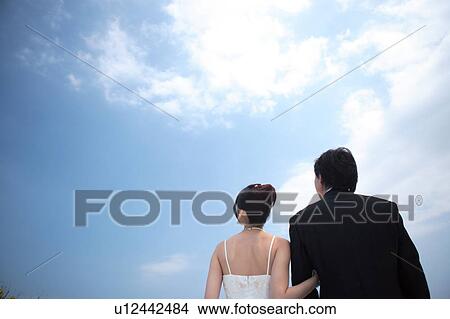 Rear view of bride and groom looking at sky View Large Photo Image Picture - Rear view of bride and groom looking at sky. Fotosearch