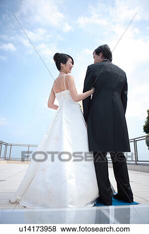 Stock Photo - Rear view of bride and groom looking at each other. Fotosearch