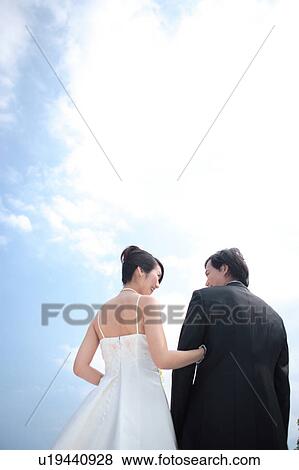 Stock Photo - Rear view of bride and groom looking at each other. Fotosearch