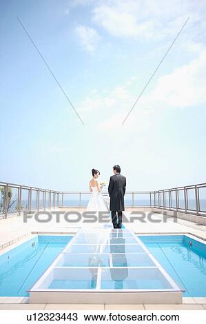 Stock Image - Rear view of bride and groom standing . Fotosearch