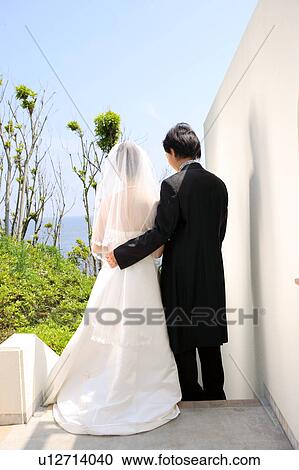 Stock Image - Rear view of bride and groom standing. Fotosearch