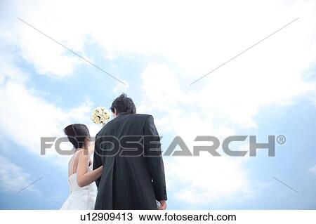 Stock Image - Rear view of bride and groom standing. Fotosearch