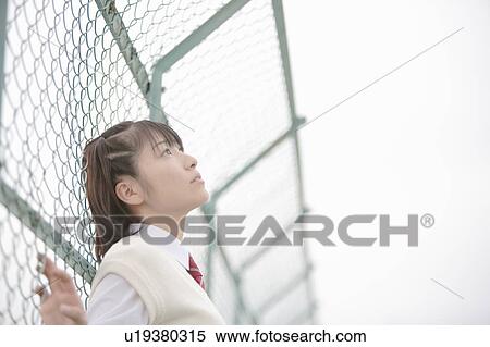 Stock Photography - High school girl leaning against fence. Fotosearch