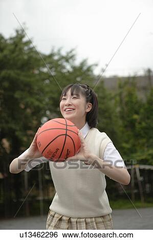 Stock Photograph - High school girl playing basketball in schoolyard. Fotosearch