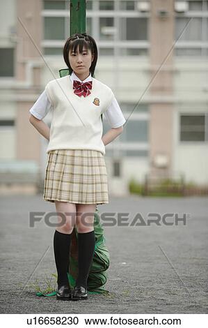 Stock Image - High school girl standing in schoolyard. Fotosearch