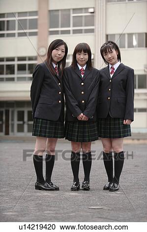 Stock Image - Three high school girls standing in schoolyard. Fotosearch
