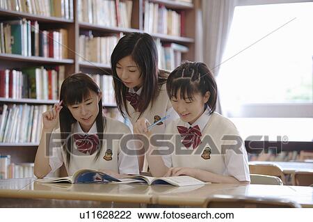 Stock Image - Three high school girls studying in library. Fotosearch