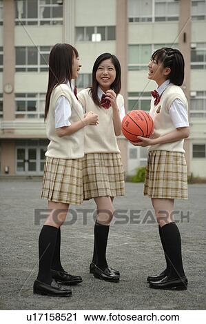 Stock Image - Three high school girls talking in schoolyard. Fotosearch