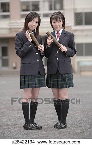 Picture - Two high school girls holding graduation certificates. Fotosearch