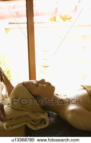 Stock Image - Young woman lying down on massage table. Fotosearch