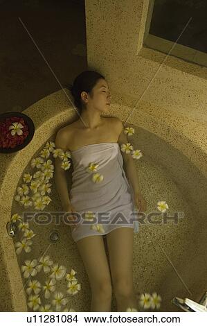 Young woman taking bath with flower petals View Large Photo Image Picture - Young woman taking bath with flower petals. Fotosearch