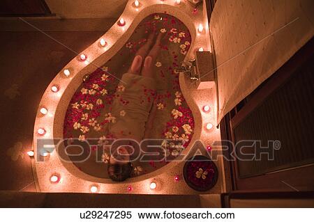 Stock Photography - Young woman taking bath with flower petals. Fotosearch