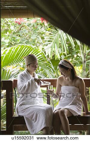 Stock Image - Young women sitting on bench. Fotosearch