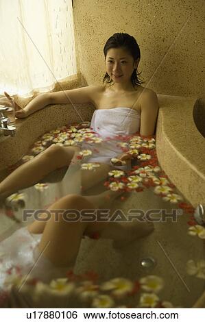 Stock Photograph - Young women taking bath with flower petals. Fotosearch