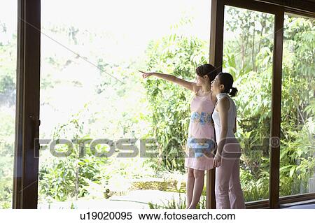 Stock Photography - Two young women looking out window. Fotosearch