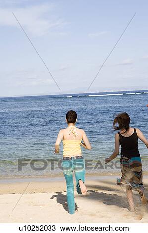 Two young women running on beach View Large Photo Image Stock Image - Two young women running on beach. Fotosearch