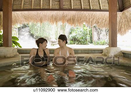 Stock Image - Two young women soaking in hot tub. Fotosearch