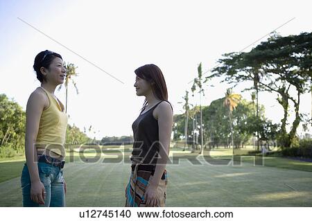 Two young women standing and talking View Large Photo Image Stock Image - Two young women standing and talking. Fotosearch