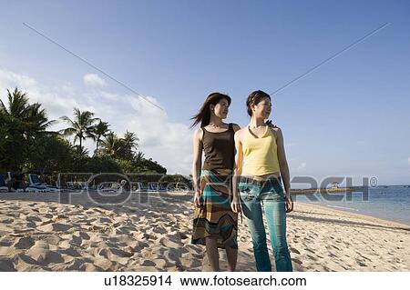 Picture - Two young women standing on beach. Fotosearch