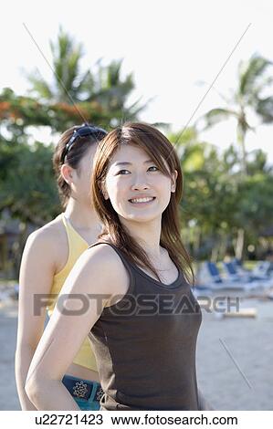 Stock Image - Two young women standing on beach. Fotosearch