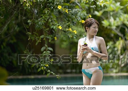 Young woman in bikini holding glass of juice View Large Photo Image Stock Image - Young woman in bikini holding glass of juice. Fotosearch