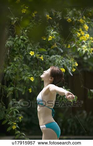 Stock Photo - Young woman in bikini stretching arms. Fotosearch