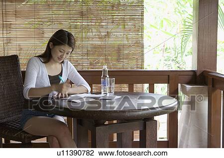 Young woman sitting at table writing View Large Photo Image Stock Image - Young woman sitting at table writing. Fotosearch