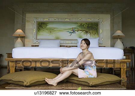 Stock Photo - Young woman sitting on cushion. Fotosearch