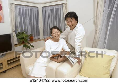 Mature couple sitting with magazine View Large Photo Image Stock Image - Mature couple sitting with magazine. Fotosearch