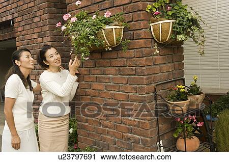 Stock Image - Mature women standing in front of house. Fotosearch