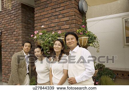 Stock Photo - Two mature couple standing in front of house. Fotosearch