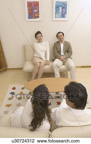 Stock Image - Two mature couples talking in living room. Fotosearch