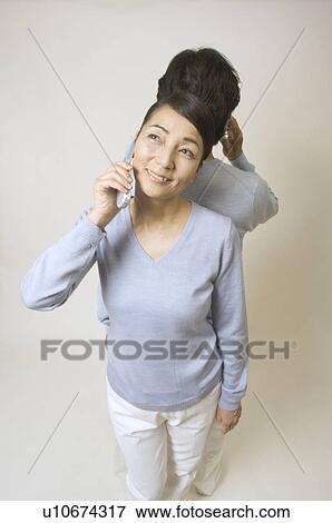 Mature couple standing back to back, talking on mobile phones View Large Photo Image Stock Photo - Mature couple standing back to back, talking on mobile phones. Fotosearch