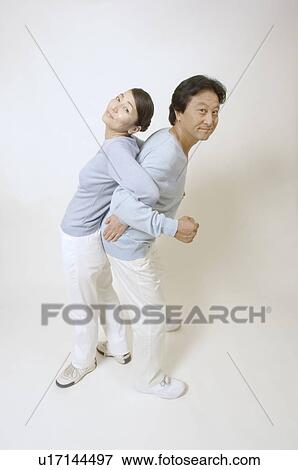 Stock Photo - Mature couple standing back to back, arms locked. Fotosearch