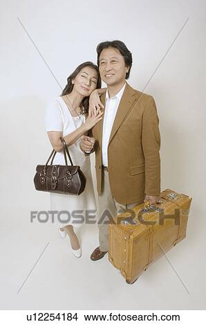 Picture - Mature couple standing with suitcase and bag. Fotosearch